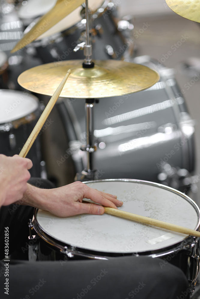 Fototapeta premium Young adult men and women learn to play drums at school. Hobbies and pastime.