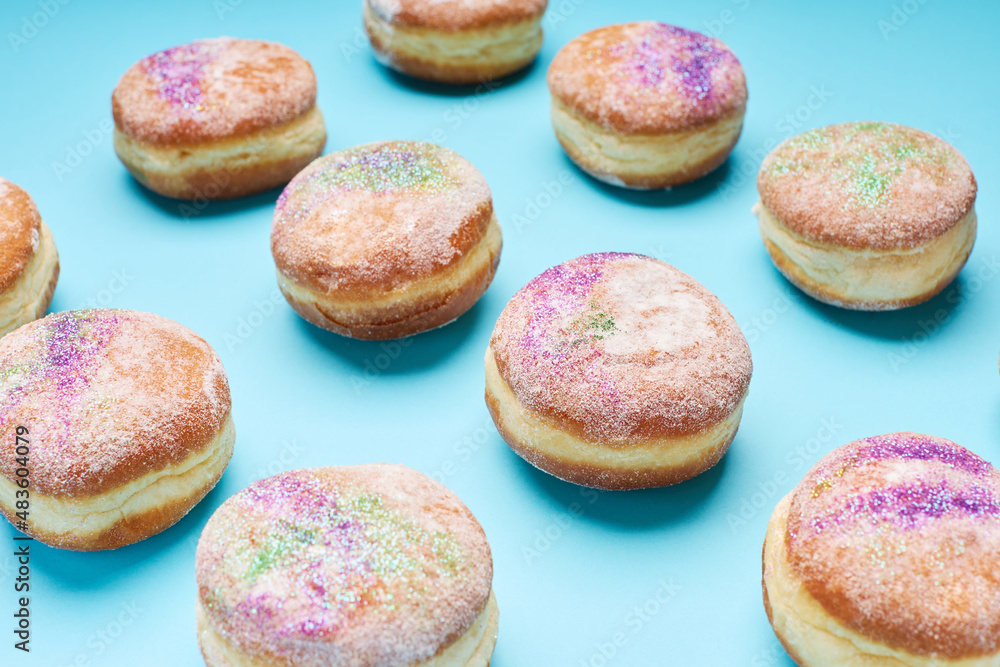 Donuts sprinkled with traditional Mardi Gras colors on blue background.