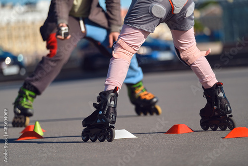 Child learns to roller skate in the city. The coach is filming a student on roller skates.