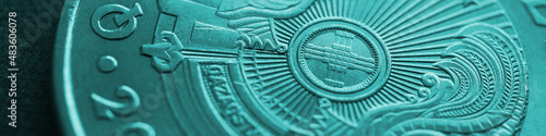 Fragment of Kazakh 50 tenge coin with the country emblem and focus on shanyrak. Close-up. Turquoise tinted banner or headline for Kazakh economy or state. Macro