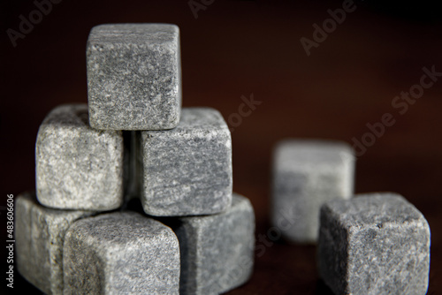Set of whiskey chiller grey soapstone stones close up on the dark wooden background. Shallow depth of field vintage style picture