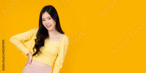 Surprised happy beauty asian woman look at camera in excitement Expressive facial expressions Presenting product Beautiful girl act like a showing something Isolated on yellow background Arm akimbo