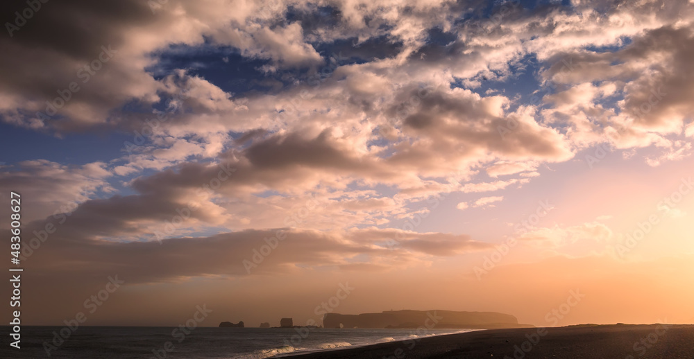 Fantastic landscape with picturescue sky in Iceland during sunset, View from Reynisfjara black sand beach ocean horizon an rock formation arch at Dyrholaey, Kirkjufjara. most popular touristic area