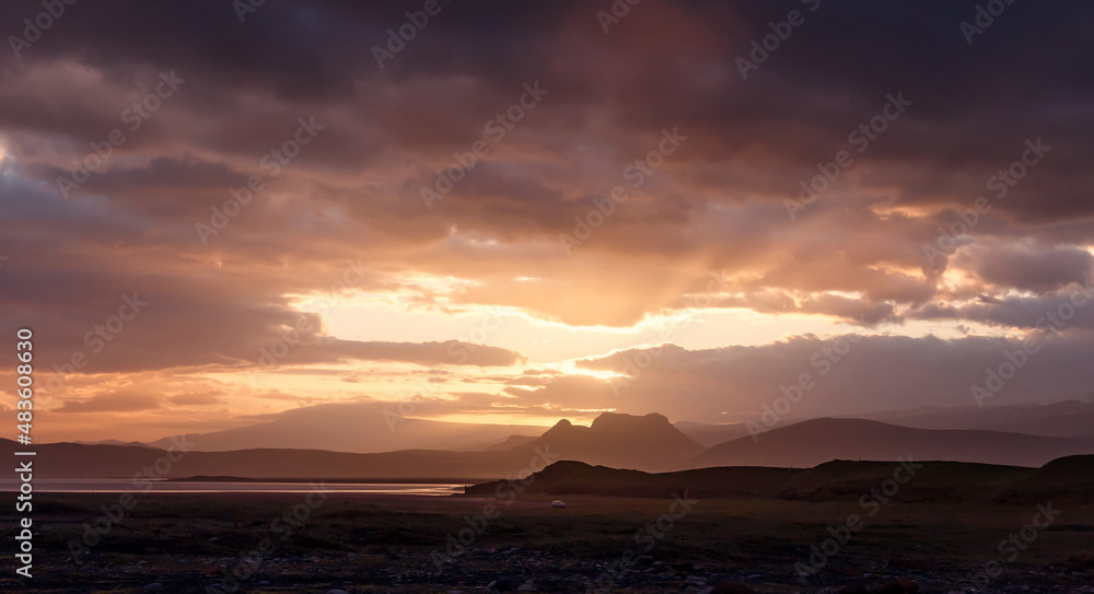 Stunning sunset over the mountains of Iceland. Fantastic view on landscape in Iceland. One small car driving on the black sand beach during sunset. Travel on the car is a Lifestyle, adventure concept.