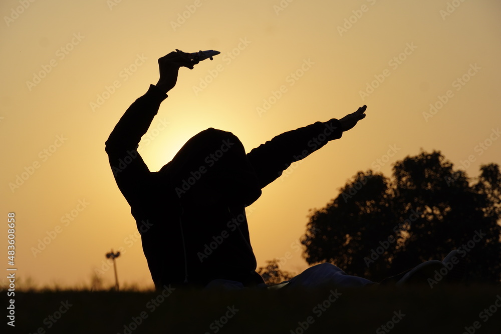 Happy young boy with a toy airplane on a sunset background over a wheat field