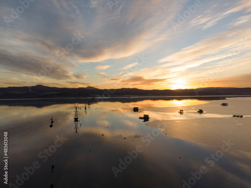 Sunset above the lake. Beautiful lake in nature, aerial drone view. Aerial ropeway bucket above water. Sunset over industry cranes and cable railway. 