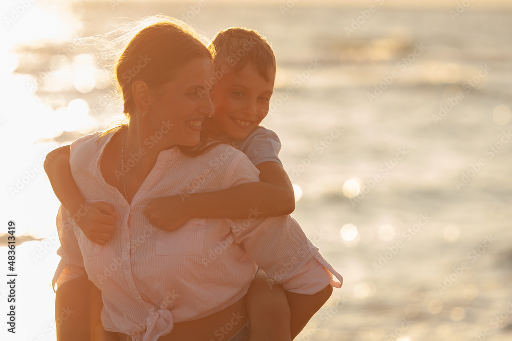 Fototapeta premium Mom and her son hugging and smiling together over blue sea view