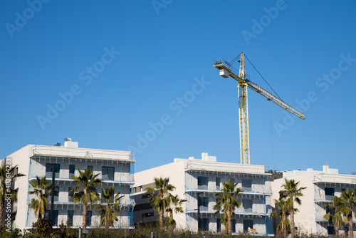 New homes construction in Spain, crane building new house, new street in Sitges with palms, real estate mortgage