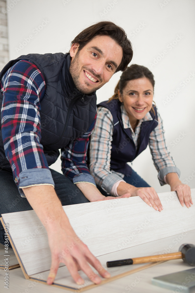 Obraz premium man and woman laying wood panel flooring in a house