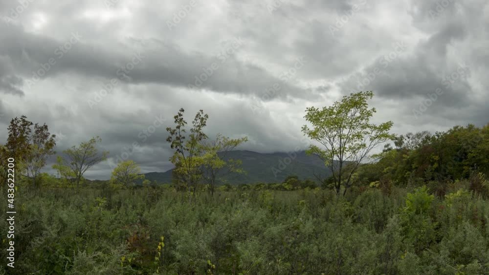 The top of the mountain is covered by clouds. Rain clouds fly across the sky. Timelapse. Summer.