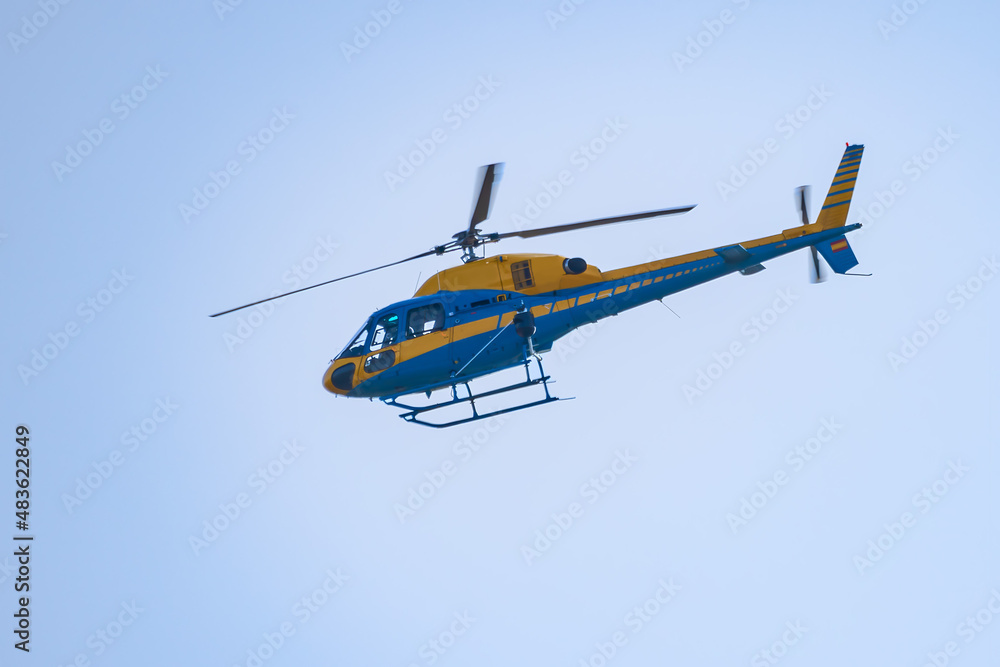 Fototapeta premium Yellow and blue Helicopter of Traffic surveillance Patrolling the roads and highways to control reckless driving.
