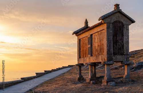typical Galician granary beside the sea at sunset in Baiona, Galicia, Spain.