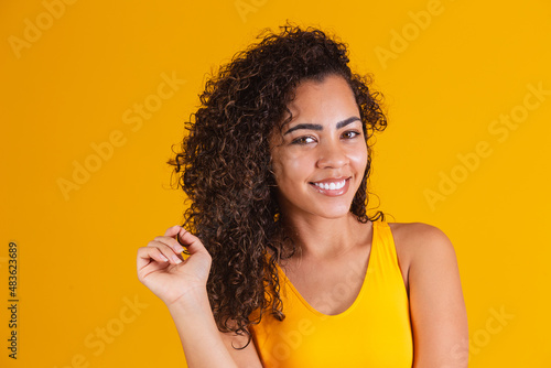 Fotografie Happy laughing African American woman with her curly hair on yellow background