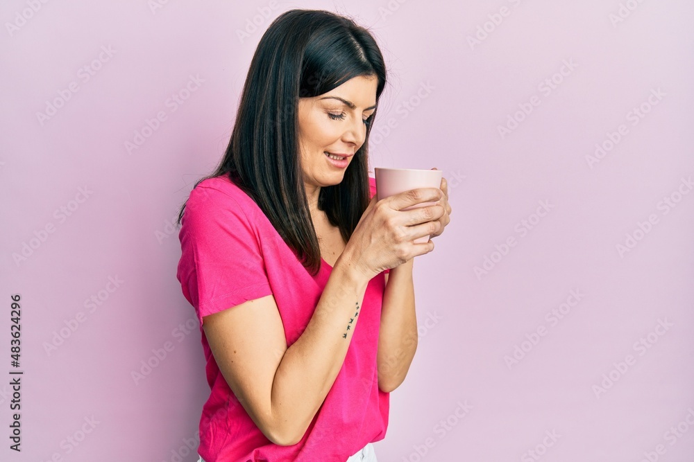 Young hispanic woman drinking a cup of coffee surprised with an idea or question pointing finger with happy face, number one Young hispanic woman drinking a cup of coffee surprised with an idea or question pointing finger with happy face, number one