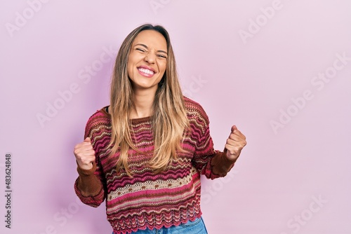 Beautiful hispanic woman wearing hippie sweater excited for success with arms raised and eyes closed celebrating victory smiling. winner concept.