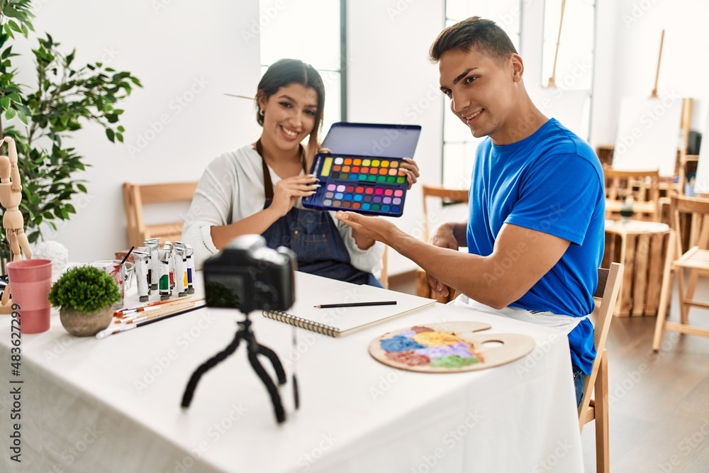 Two students smiling happy recording paint class using camera at art school. Two students smiling happy recording paint class using camera at art school.