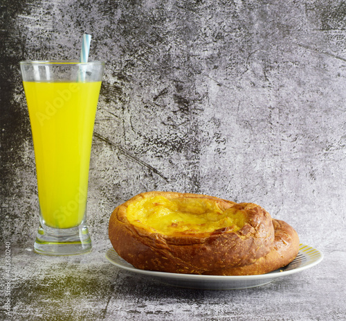 Sweet and traditional ensaimada covered with burnt cream, accompanied by an orange soda.  photo