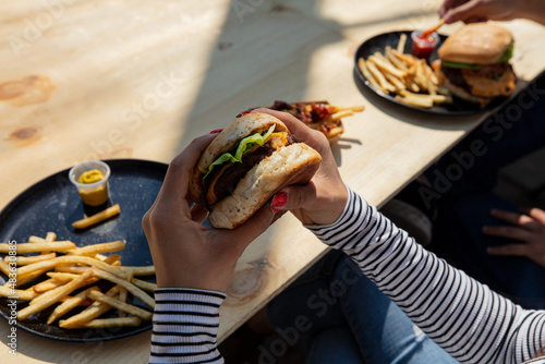 Woman hands holding burger outdoors