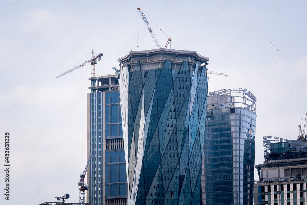 Fototapeta premium construction of skyscrapers and cranes, office buildings with glass facades, selective focus