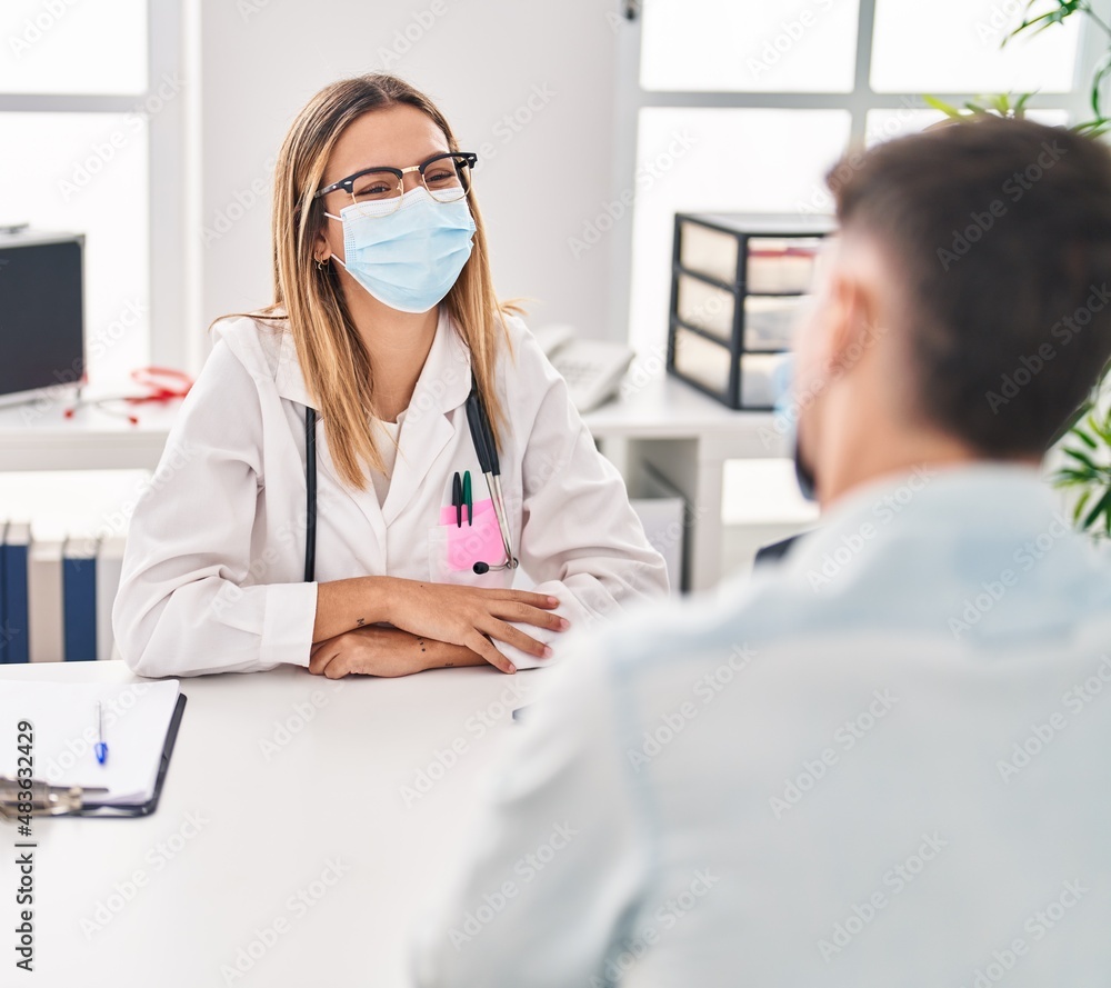 Young man and woman doctor and patient wearing medical mask at clinic