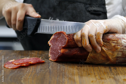 carnicero cortando lonchas lomo ibérico con cuchillo photo