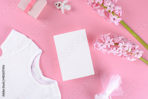Baby girl shower invitation card mockup with baby accessories girl bodysuit, nipple or baby's dummy, gift box and confetti and pink hyacinth flowers with copy space on pink pastel color background © Anna Fedorova