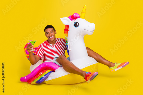 Full size photo of guy swim water unicorn ring enjoy punch wear red striped t-shirt isolated over yellow bright color background