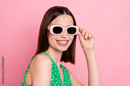 Profile side photo of young cheerful woman hand touch eyeglasses isolated over pink color background