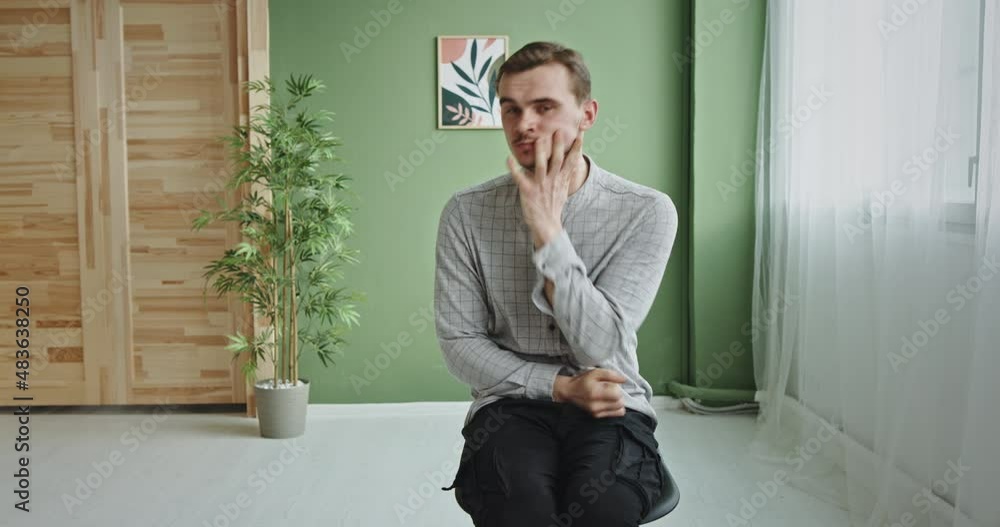 Nervous man sitting on chair in room Nervous man sitting on chair in room