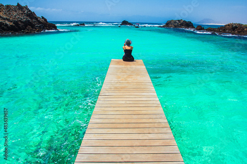 Girl looking at the sea at the end of wooden jetty in Isla de Lobos, Canary Island.
