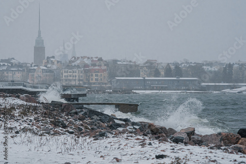 View of Helsinki from the seashore in a winter storm, waves breaking on a rocky shore. Finland weather..