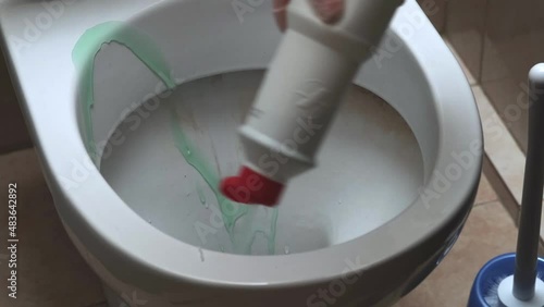 A gloved hand treats the toilet with a cleaning agent. Homework.