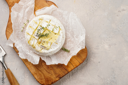 Fotografie Oven baked camembert cheese with lye baguette bread on wooden board, grey concrete surface