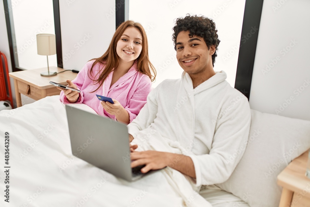 Young couple smiling happy using laptop, smartphone and credit card at bedroom. Young couple smiling happy using laptop, smartphone and credit card at bedroom.