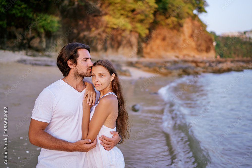 Love and romance. Honeymoon on the sea shore. Happy loving couple embracing on the beach.