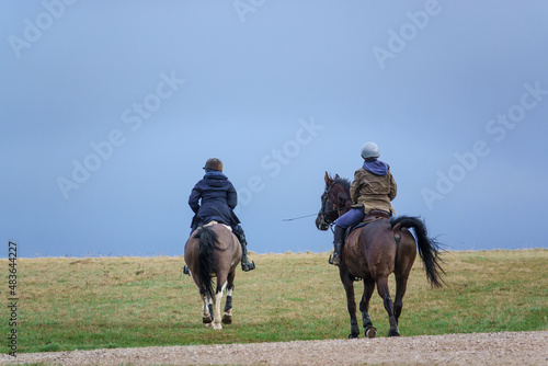 horse riding in open countryside under a blue grey cloud winter sky 