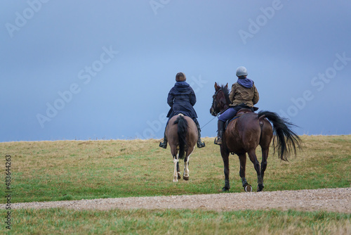 horse riding in open countryside under a blue grey cloud winter sky  © Martin