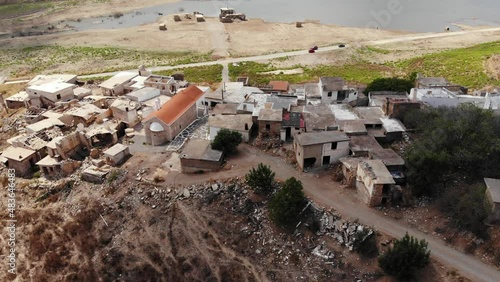 Aerial shot of forsaken Sfendyli village, located in Aposelemis dam reservoir. Destroyed by flood houses, only one Church building unbroken. Shallow water on background, camera fly up and tilt down photo