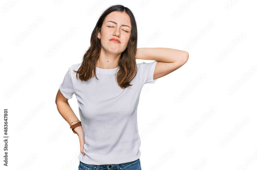 Young beautiful woman wearing casual white t shirt suffering of neck ache injury, touching neck with hand, muscular pain Young beautiful woman wearing casual white t shirt suffering of neck ache injury, touching neck with hand, muscular pain
