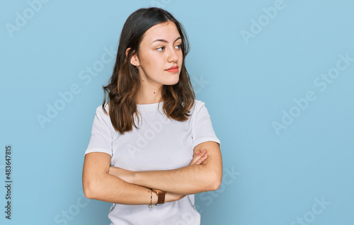 Young beautiful woman wearing casual white t shirt looking to the side with arms crossed convinced and confident
