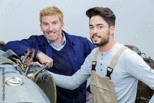 Photos mechanic and colleague looking at camera