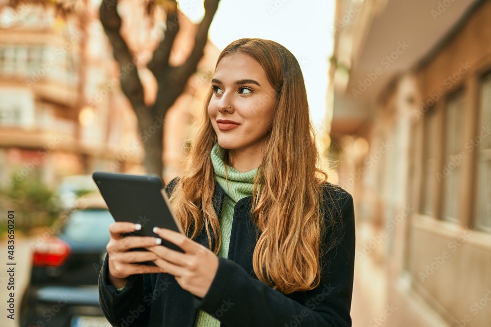 Young blonde girl smiling happy using touchpad at the city. Young blonde girl smiling happy using touchpad at the city.