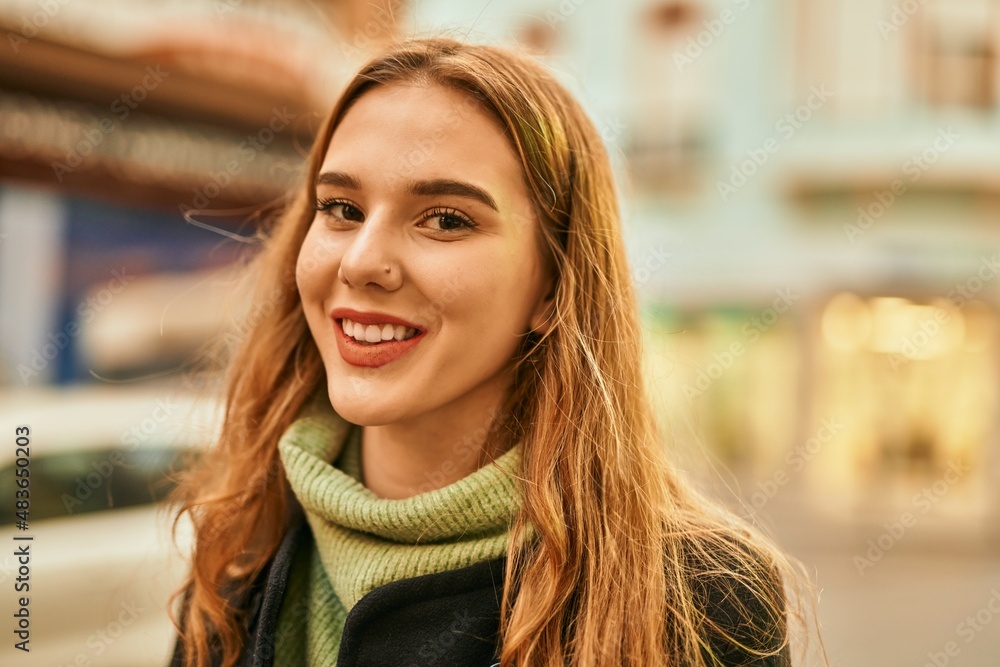 Young blonde girl smiling happy standing at the city.