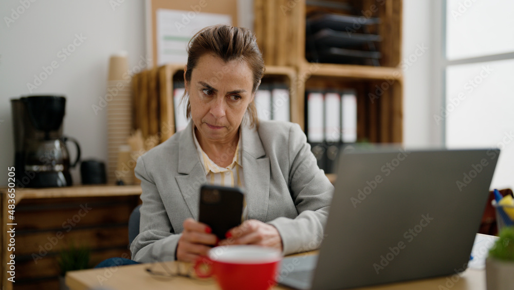 Middle age hispanic woman business worker using smartphone at office Middle age hispanic woman business worker using smartphone at office