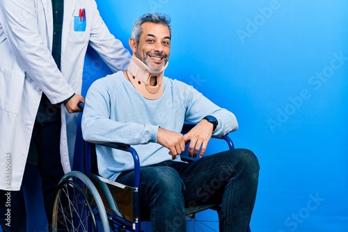Fotografering Handsome middle age man with grey hair on wheelchair wearing cervical collar with a happy and cool smile on face