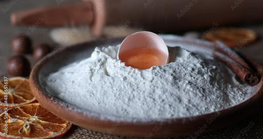 Rustic style still life of organic food ingredients for homemade baking with white flour and egg yolk inside half of egg shell. Flour powder sift at pile of flour in traditional wooden bowl Rustic style still life of organic food ingredients for homemade baking with white flour and egg yolk inside half of egg shell. Flour powder sift at pile of flour in traditional wooden bowl