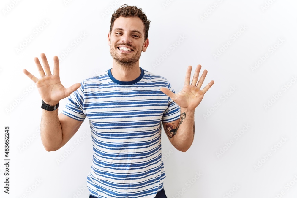 Handsome young man standing over isolated background showing and pointing up with fingers number ten while smiling confident and happy. Handsome young man standing over isolated background showing and pointing up with fingers number ten while smiling confident and happy.