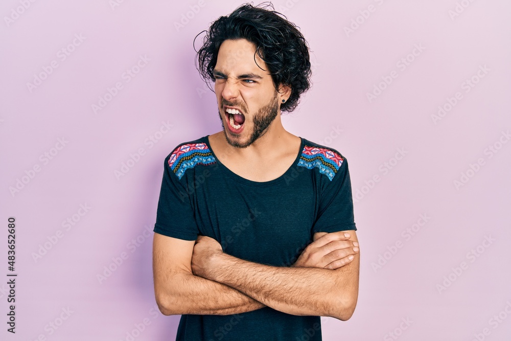 Handsome hispanic man with arms crossed gesture angry and mad screaming frustrated and furious, shouting with anger. rage and aggressive concept. Handsome hispanic man with arms crossed gesture angry and mad screaming frustrated and furious, shouting with anger. rage and aggressive concept.