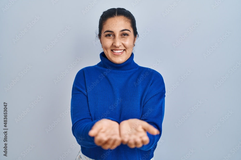 Young hispanic woman standing over isolated background smiling with hands palms together receiving or giving gesture. hold and protection Young hispanic woman standing over isolated background smiling with hands palms together receiving or giving gesture. hold and protection