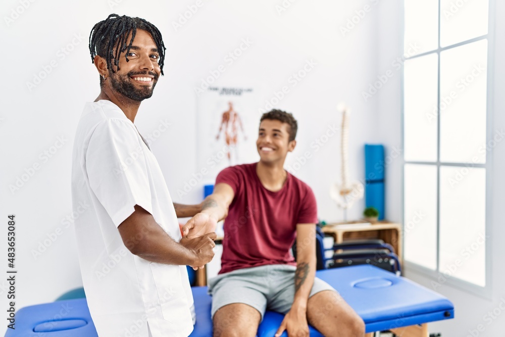 Obraz premium Two men physiptherapist and patient having rehab session stretching arm at clinic